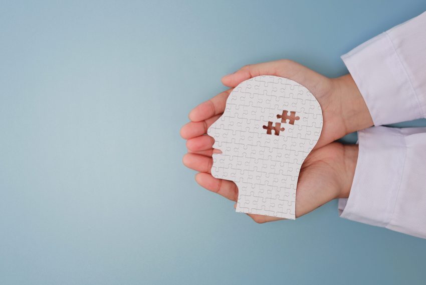 Caring doctor hand holding white paper head with puzzle piece showing visual mental health recovery concept offering gentle support